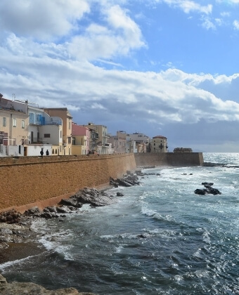 Muro parallelo a un corpo d'acqua, edifici e cielo nuvoloso.