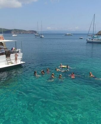Gruppo di persone nuota vicino a una barca bianca nel mare.
