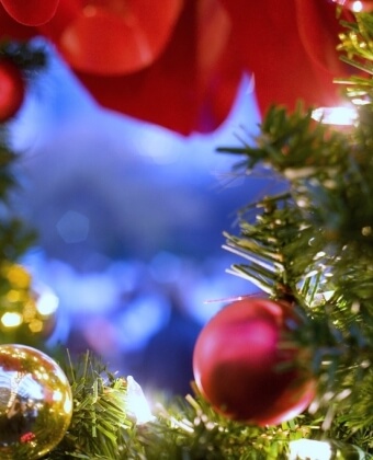 Albero di Natale decorato con ornamenti rossi e dorati, luci bianche.
