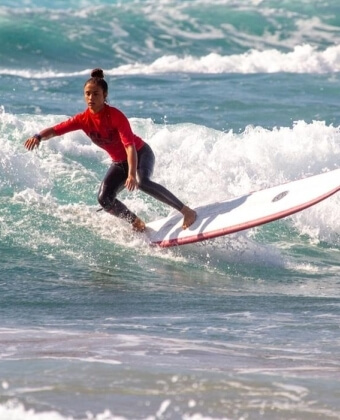 Surfista su tavola bianca con striscia rossa, indossa maglietta rossa.