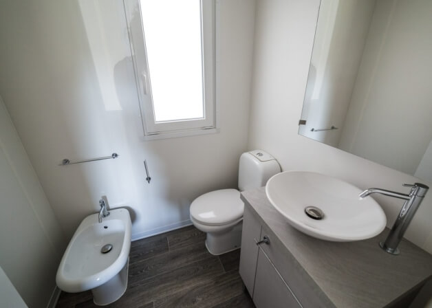 Bagno con bidet, toilet, lavabo, finestra e specchio.