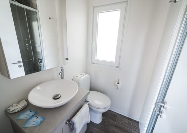 Bagno con lavabo bianco, WC, specchio e finestra.