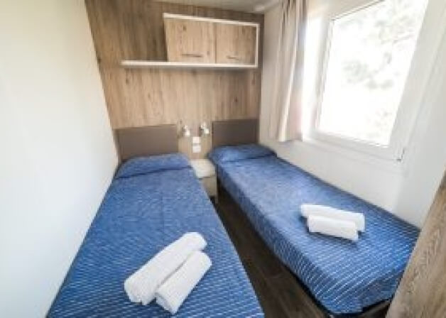 Camera d'hotel con due letti singoli e finestra con tende bianche.