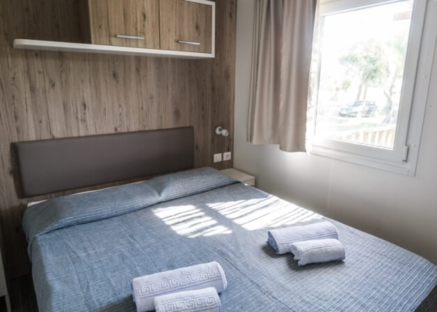 Camera da letto con letto a righe blu e bianco, testiera grigia.