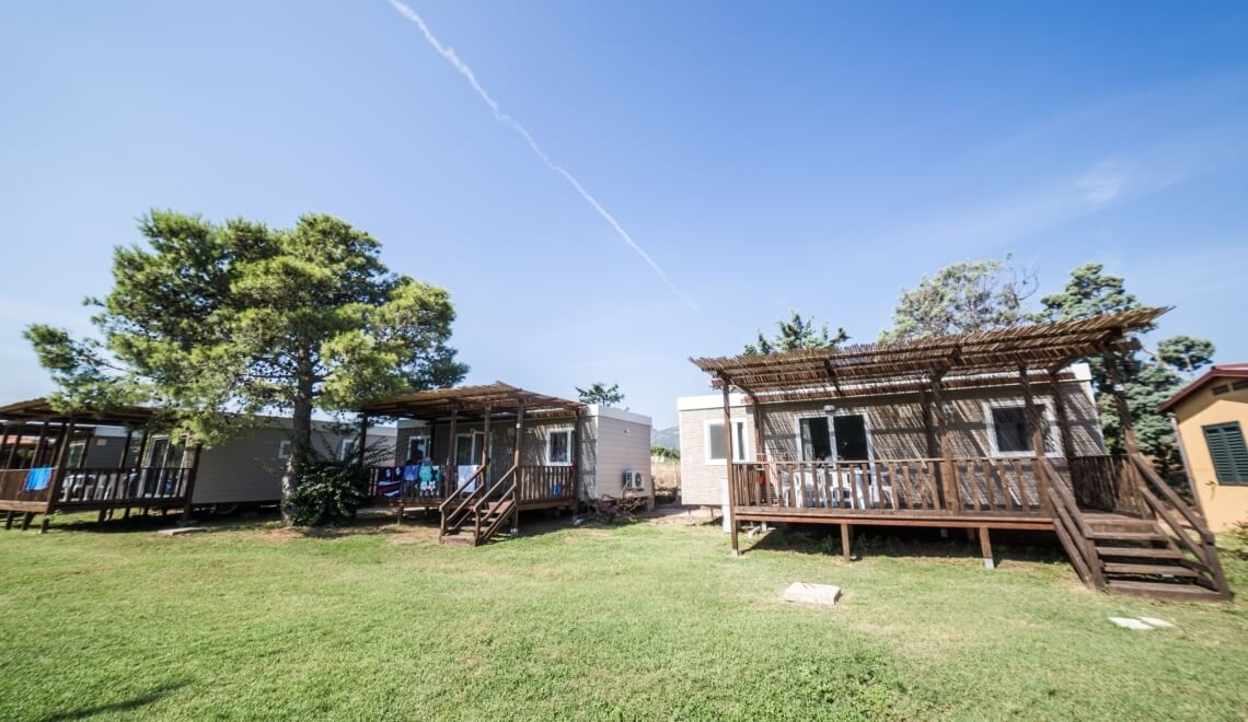 Bungalow con terrazze in un'area erbosa sotto un cielo blu.