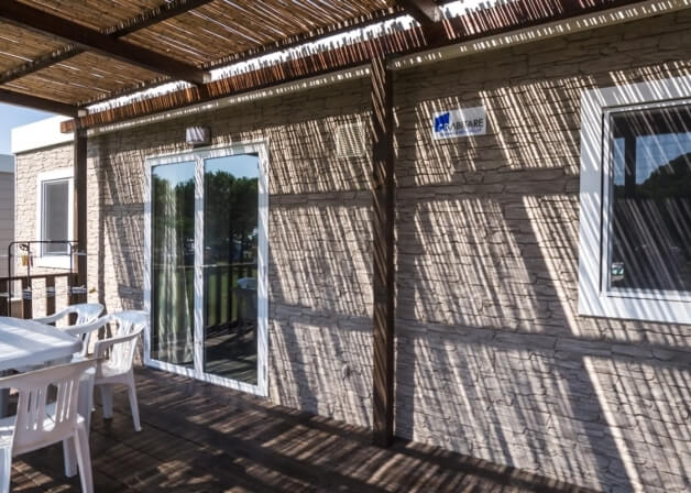 Area esterna con tavolo e sedie sotto un pergolato.