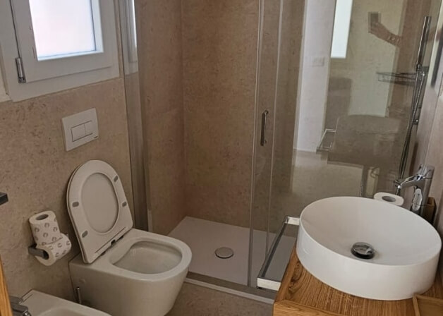Bagno moderno con WC, lavabo, doccia e finestra.
