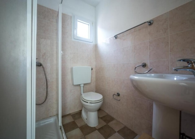 Bagno con doccia, WC, lavabo e barre per asciugamani.