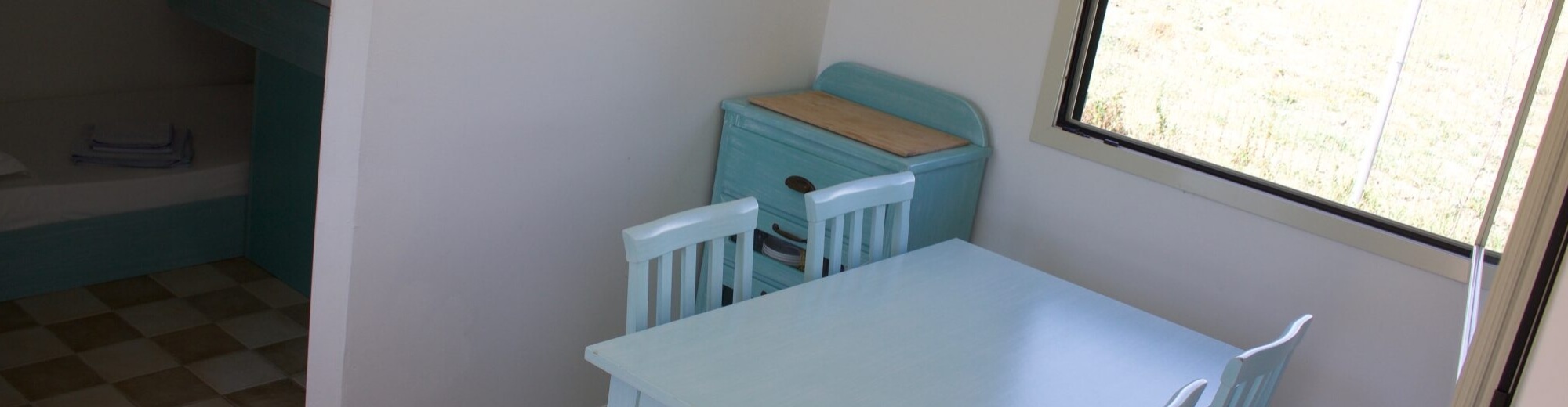 Camera d'hotel con letto, area pranzo e vista su erba secca.