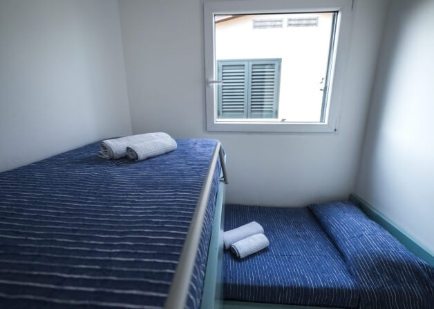 Camera con due letti, uno elevato e uno a livello del pavimento.