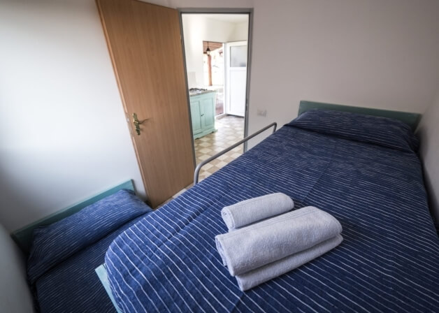 Camera d'hotel con due letti, cucina sullo sfondo.