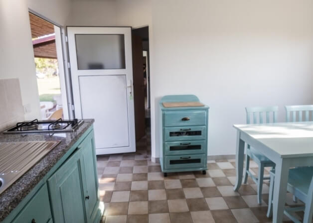 Cucina con armadi blu, piano in granito e tavolo teal.