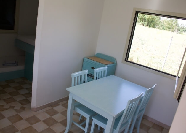 Tavolo bianco con quattro sedie in una stanza luminosa.