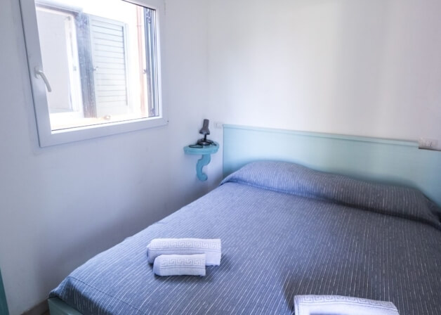 Camera d'hotel con letto a righe blu e asciugamani bianchi.