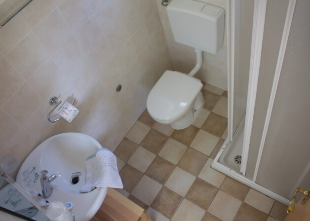 Bagno con lavabo, WC e doccia, pavimento a scacchi beige e marrone.