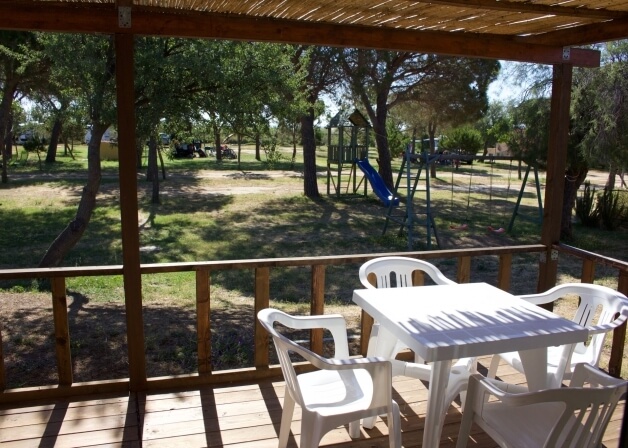 Tavolo bianco e sedie su un ponte di legno con area giochi.