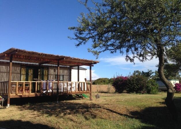 Bungalow con patio in paglia, deck bianco e fiori colorati.