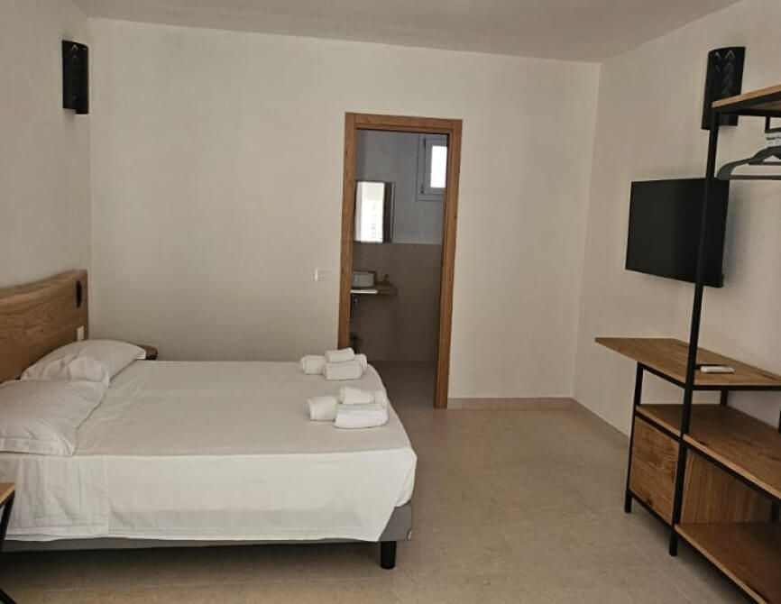 Camera d'hotel con letto, TV, e bagno visibile.