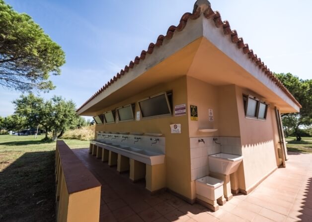 Area comune all'aperto con lavandini, finestre e alberi circostanti.