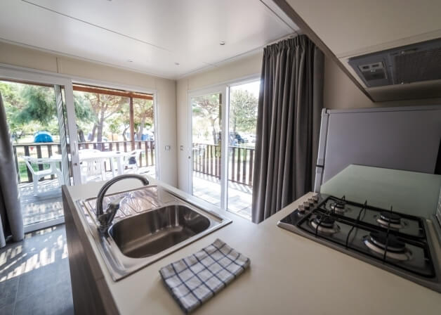 Cucina con lavello, piano cottura e porte scorrevoli verso l'esterno.