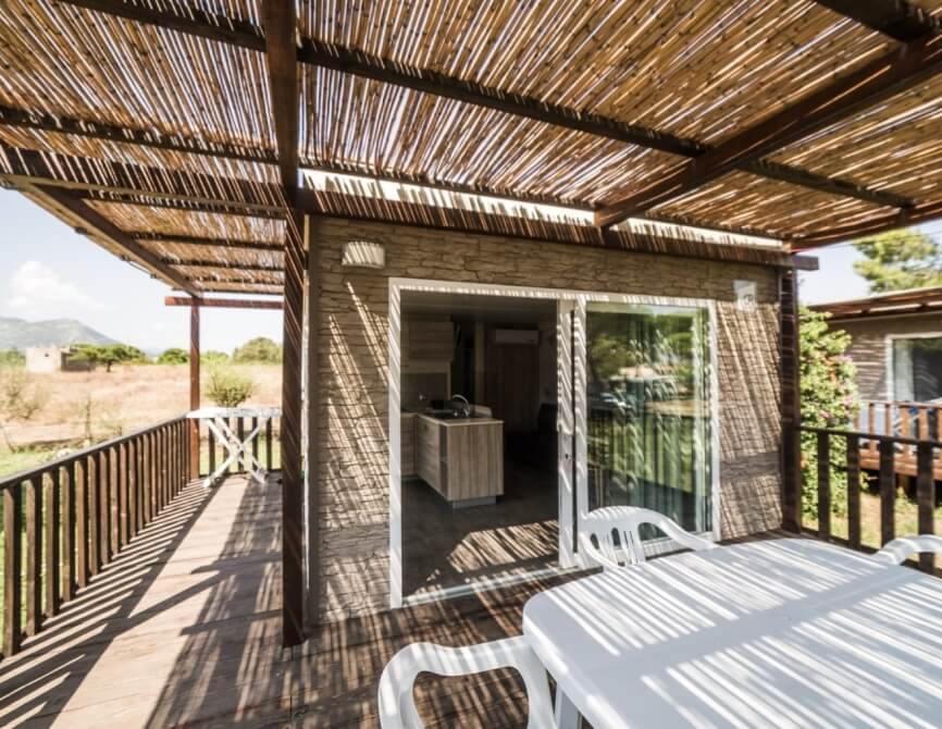 Deck with thatched roof, wooden railing, and outdoor seating.
