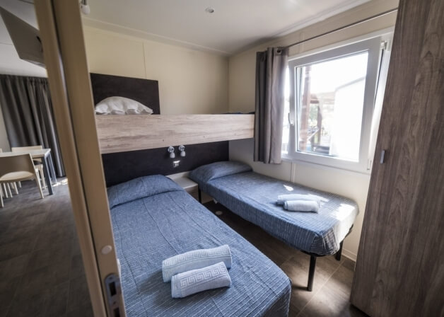 Camera con letti singoli e a castello, armadio e tavolo.