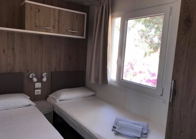 Camera d'hotel con due letti singoli e vista su piante.