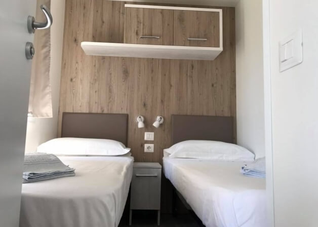 Camera d'hotel con due letti, comodino e armadietto sopra.