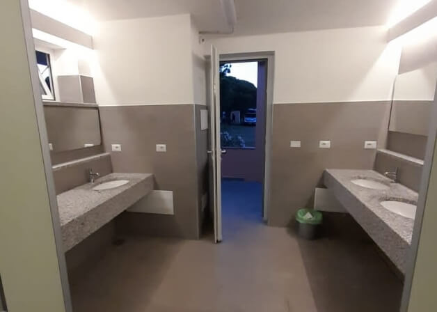 Bagno comune con due vanità, lavandini e specchio.