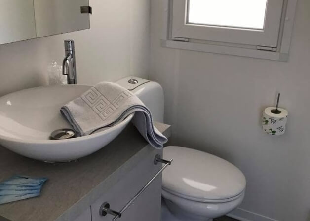 Bagno con toilet, lavandino, specchio parziale e asciugamano.