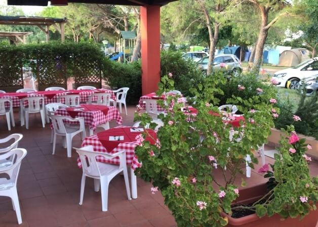 Area pranzo all'aperto con tavoli a scacchi rossi e bianchi.