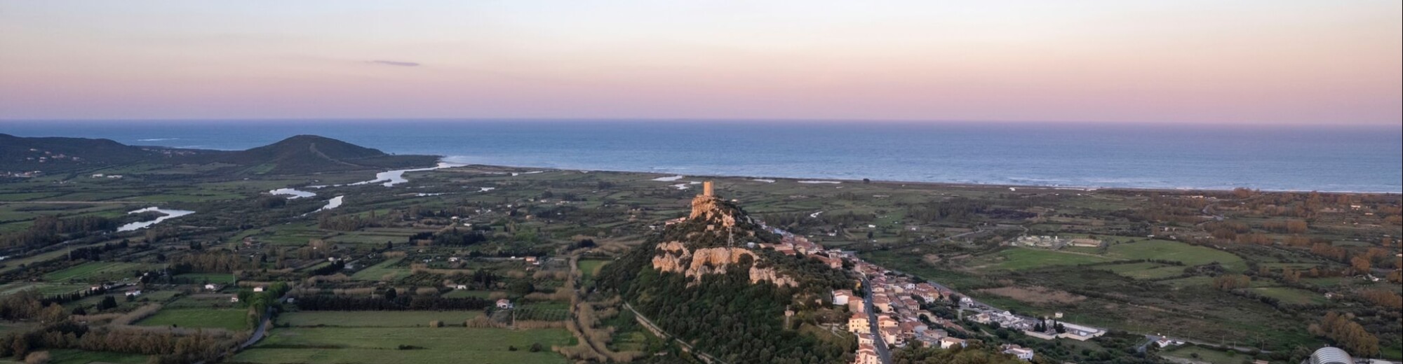 Vista aerea di un paesaggio costiero al crepuscolo con torre e villaggio.