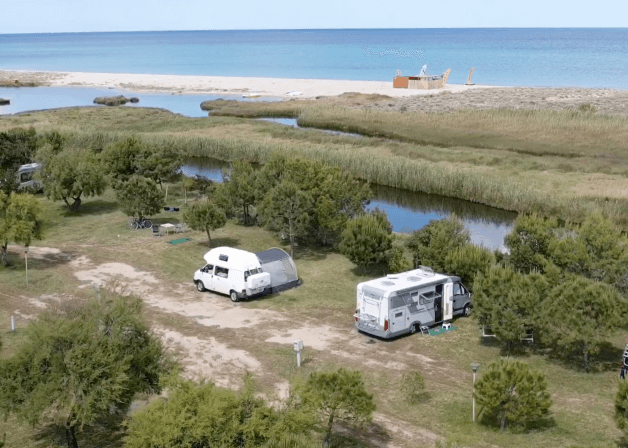 Due camper vicino a un corpo d'acqua e una spiaggia.