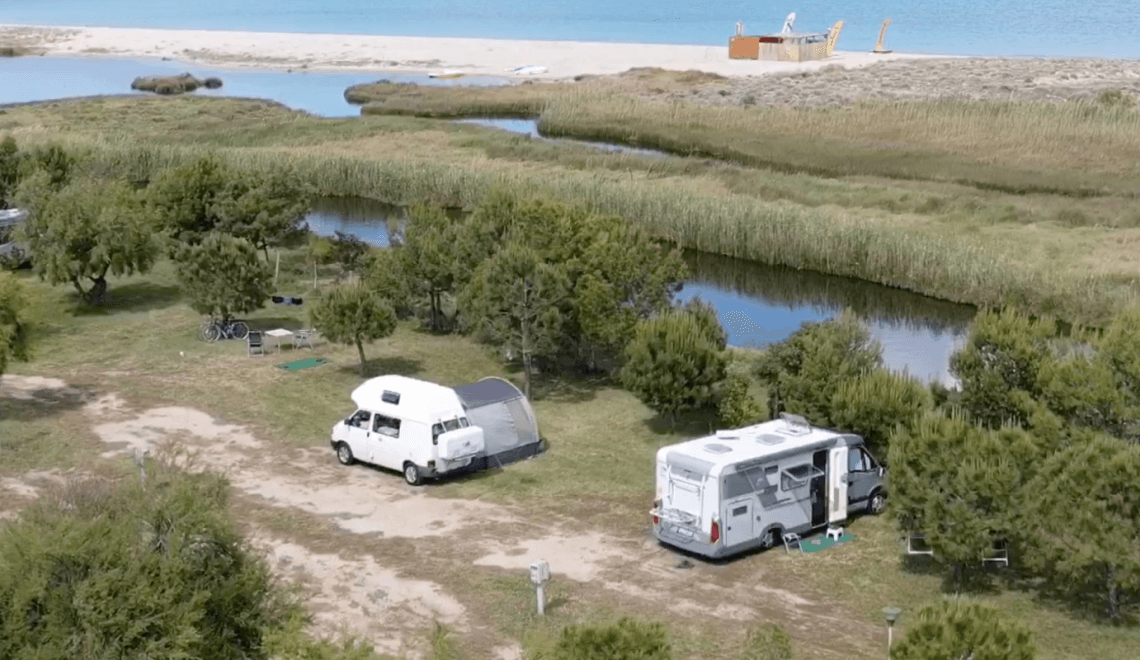 Vista aerea di un campeggio con RV, tenda e oceano.