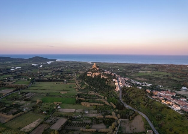 Vista aerea di un paesaggio costiero al crepuscolo con un castello.