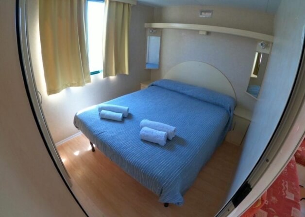 Camera d'hotel con letto a righe blu e tende gialle.