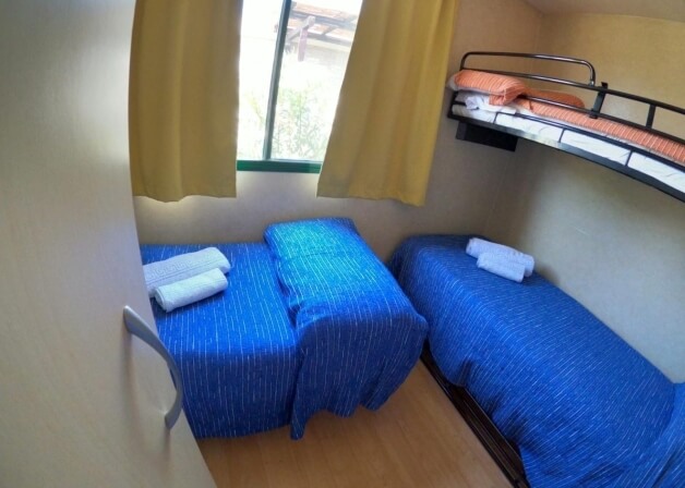 Camera con tre letti: due letti blu e un letto a castello arancione.