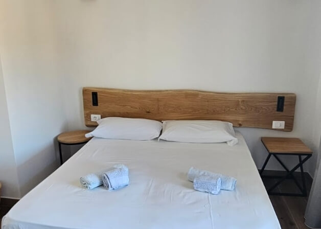 Camera d'hotel con letto, comodini e asciugamani arrotolati.