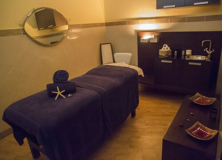 Una stanza spa serena con un tavolo da massaggio, decorazioni eleganti e un'atmosfera rilassante.