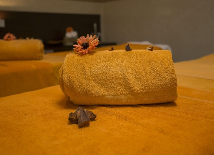 Impostazione di una spa serena con asciugamani gialli decorati, fiori e un'atmosfera di relax e professionalità.