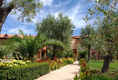 Sentiero di un giardino elegante che conduce a un edificio in stile spagnolo con fiori gialli e paesaggio curato.