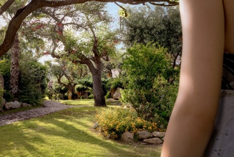Wege durch den Garten des Cruccùris Resorts, umgeben von alten Bäumen, natürlichem Schatten und Ruhe. Ein Ort zum Gehen ohne Ziel, geschaffen, um das Tempo zu verlangsamen.