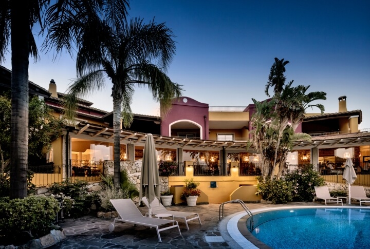 Vista serale del Cruccùris Resort di Villasimius, con piscina illuminata, giardino mediterraneo e spazi comuni immersi nel silenzio.