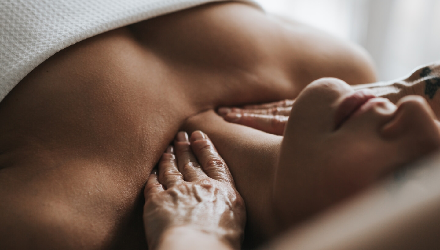 Person receiving a massage with oil, partially covered by white cloth.