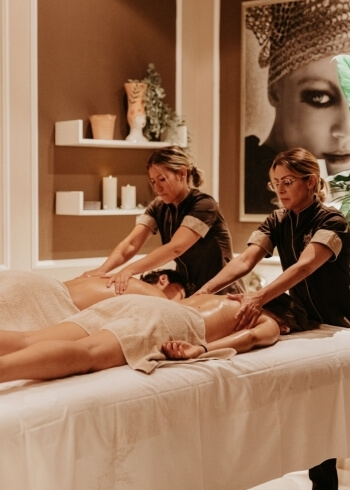 Due donne massaggiano due persone in un centro benessere.