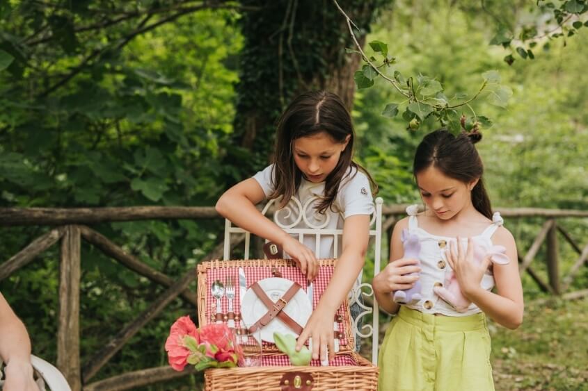 Due ragazze all'aperto con un cestino da picnic e fiori.