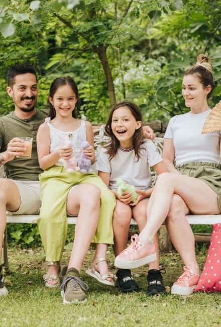 Famiglia di quattro persone seduta su una panchina all'aperto.