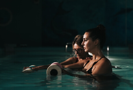 Due donne in piscina con attrezzatura per esercizi acquatici.
