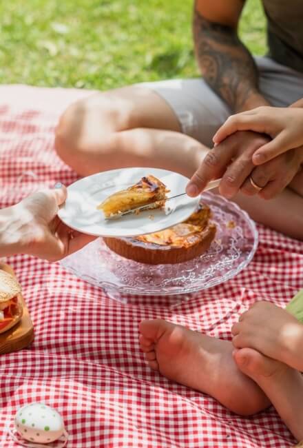 Coperta a scacchi con torta, sandwich e uovo decorativo.