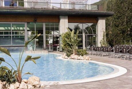 Piscina blu con sedie a sdraio e piante verdi circostanti.